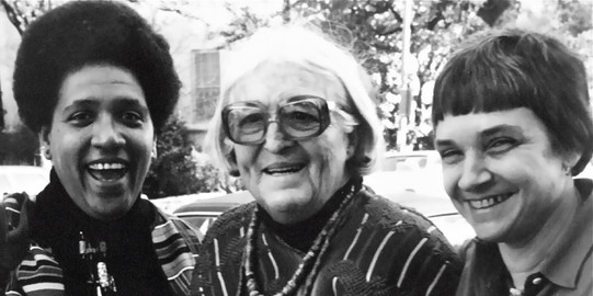 Drei Frauen stehen nebeneinander und lachen in die Kamera