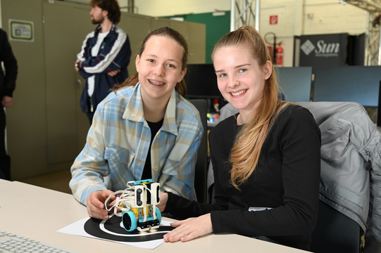 Zwei Schülerinnen präsentieren einen kleinen Roboter