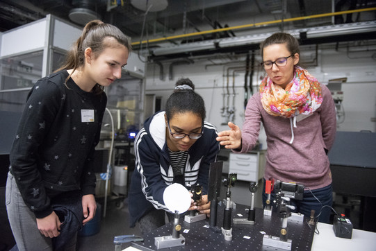 Drei jungen Frauen experimentierenn zusammen mit einem Laser