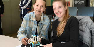 Zwei Schülerinnen präsentieren einen kleinen Roboter