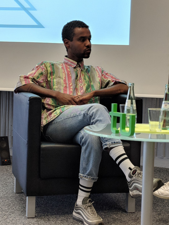 Moderator und Aktivist Tarik Tesfu sitzt in einer Gesprächsrunde